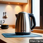 전기주전자 소음 문제 해결 - A modern kitchen scene featuring a sleek electric kettle placed on a thick, soft silicone mat on a w...